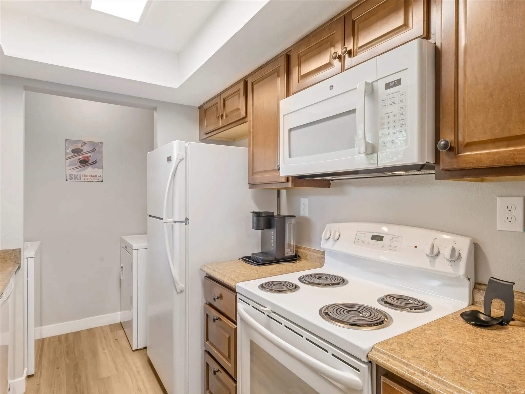 Kitchen featuring wood-finish cabinetry, built-in microwave, white electric range, and laminate countertops