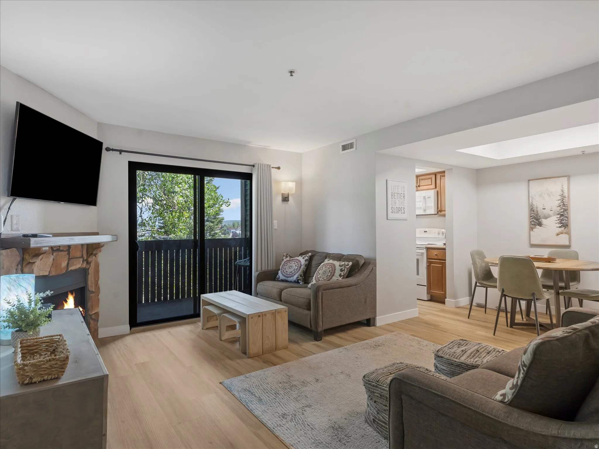 Living area featuring a stone-clad fireplace, wood-finish flooring, and a sliding glass door