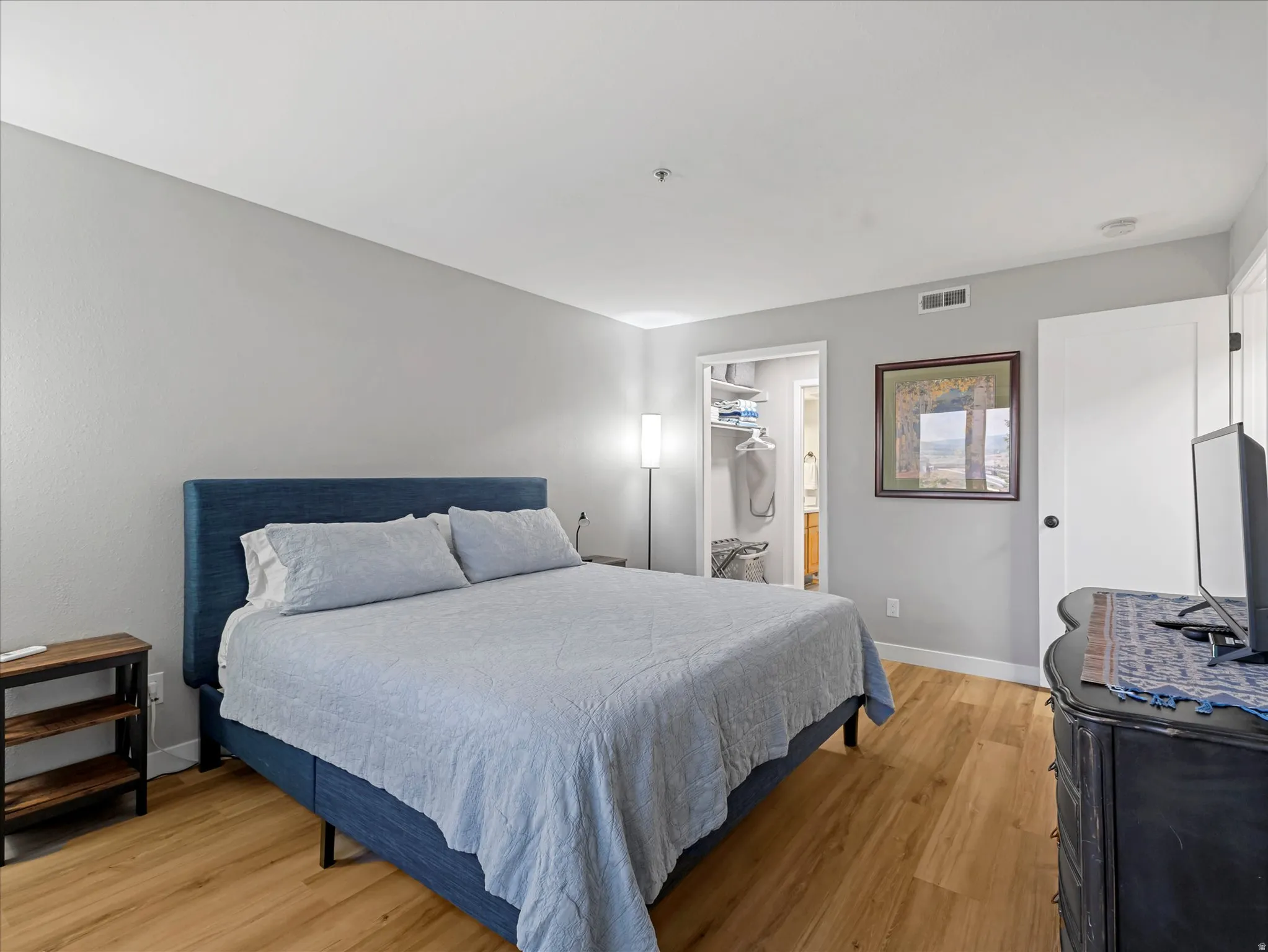 Light-toned walls, wood-finish flooring, and a recessed closet with shelving