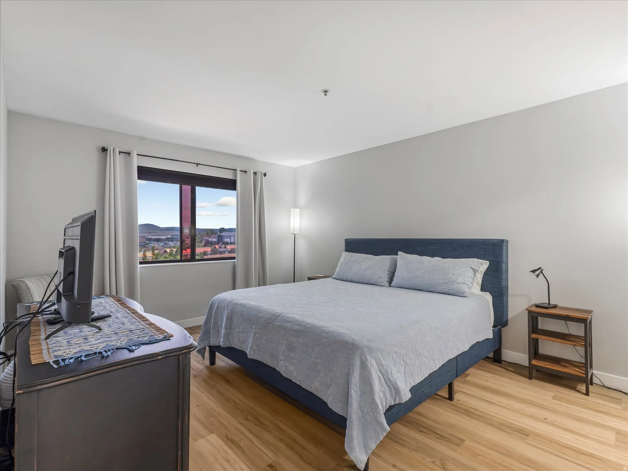 Wood-finish flooring, large window with ample natural light, and neutral wall tones