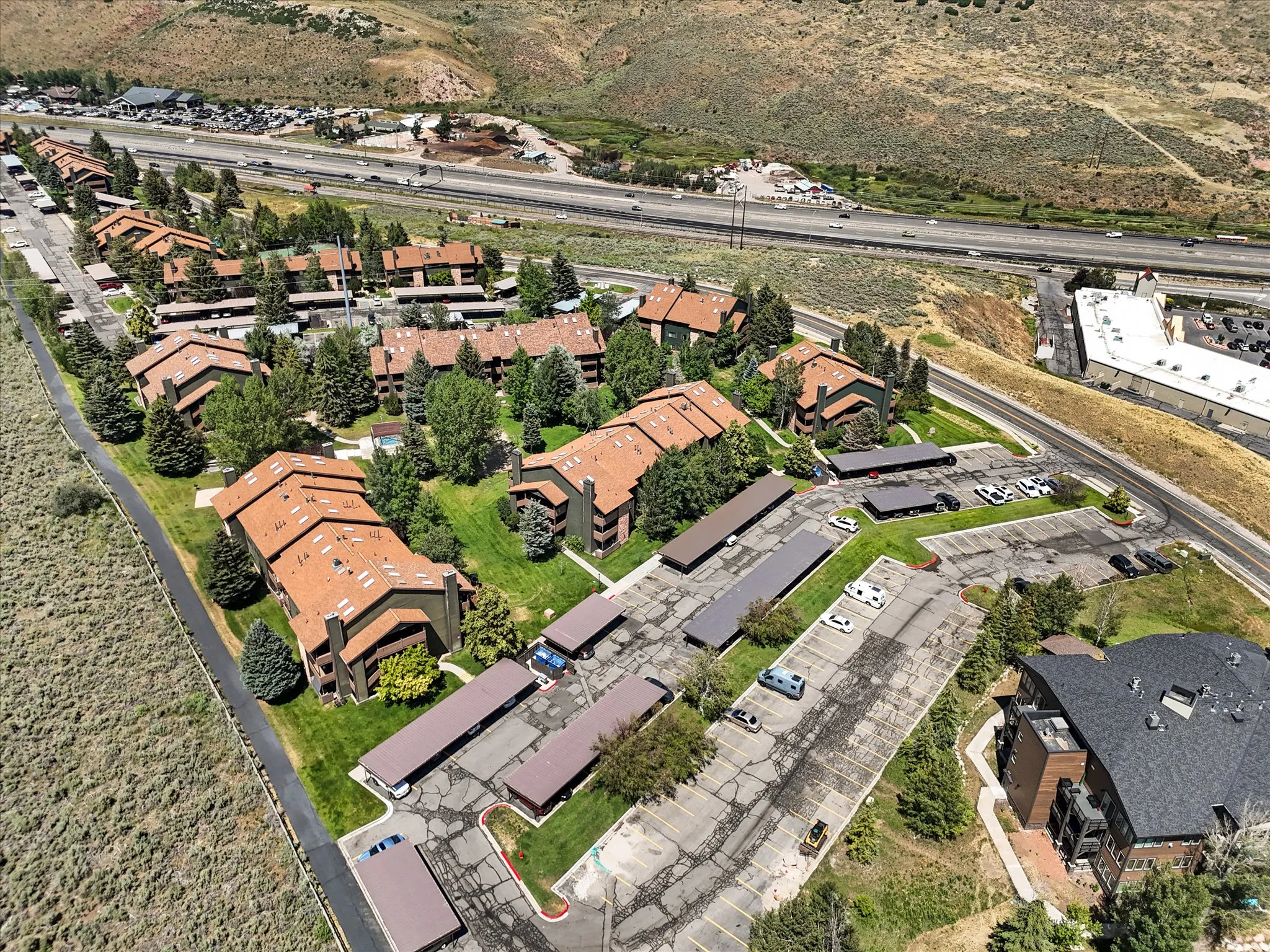 Multi-building complex with brown-toned roofs, surrounded by green landscaping and mature trees