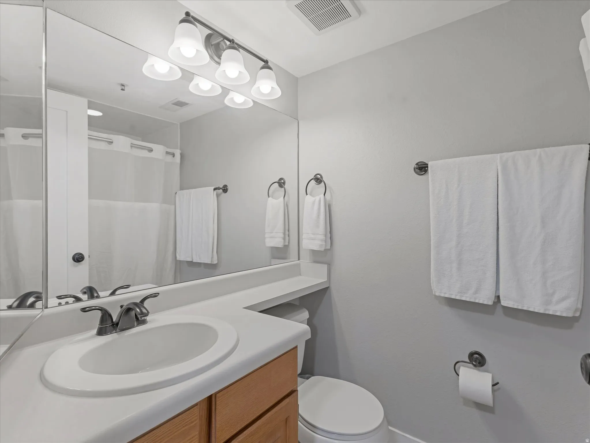 Integrated vanity with an oval sink, bronze-finish faucet, and wood-finish cabinetry