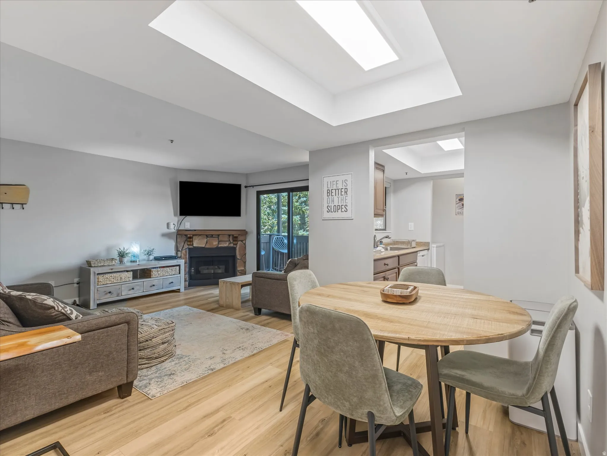 Recessed ceiling lighting, a stone-clad fireplace, wood-finish flooring, and a sliding glass door