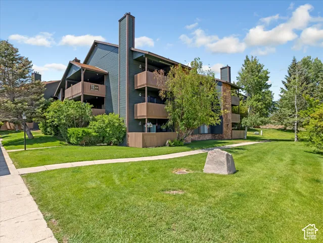 Building exterior with multiple balconies, stone veneer accents, and mature landscaping