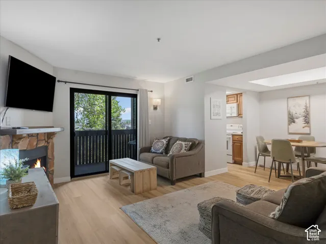 Living area featuring a stone-clad fireplace, wood-finish flooring, and a sliding glass door