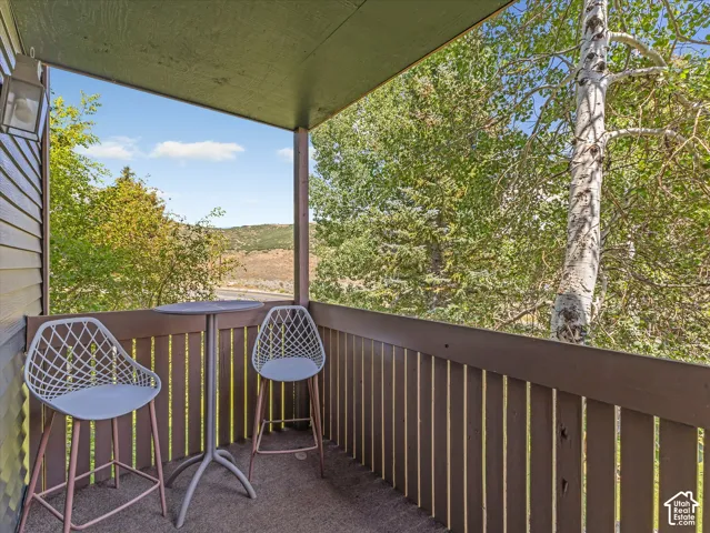 Covered outdoor balcony with a wood-slat railing, featuring an exterior wall light fixture
