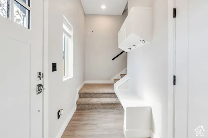 Entryway featuring wood-finish flooring, a built-in bench, and a built-in storage unit with hooks