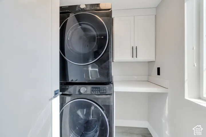 Stacked washer and dryer with an adjacent built-in countertop and white cabinetry