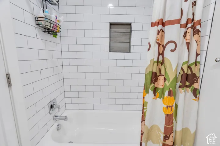 Bathtub with white subway tile surround, chrome fixtures, and built-in tiled shower niche