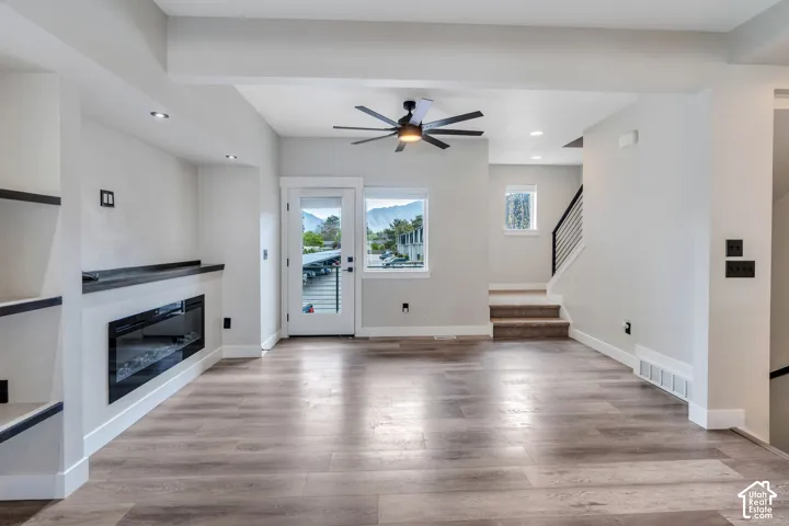 Wood-finish flooring, recessed lighting, and built-in shelving complement the electric fireplace