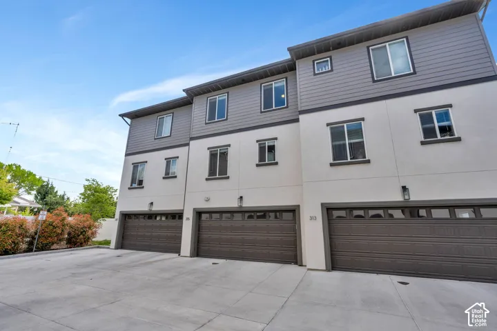 Three-story townhouse exterior featuring white stucco and gray siding