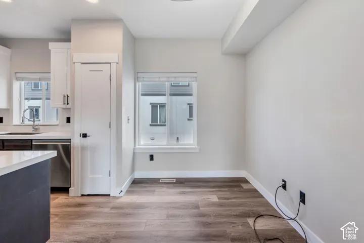 Wood-finish flooring, white walls, and a large window with blinds