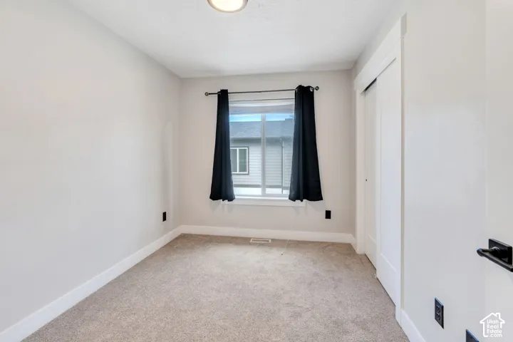 Carpeted flooring, white trim, recessed lighting, and a window with a black curtain rod