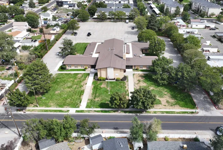Expansive paved parking area, mature perimeter trees, and substantial building footprint