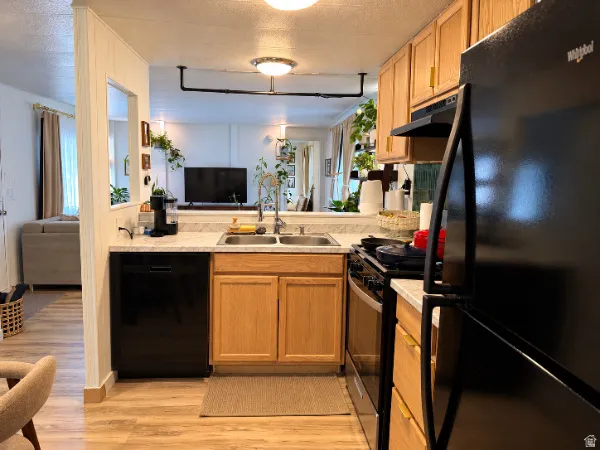 Wood-finish flooring, light wood cabinetry, black appliances, double basin sink, and laminate countertops