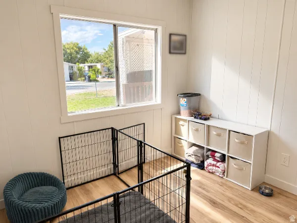 White vertical paneling, light wood-finish flooring, and a window with white trim