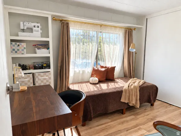 Built-in shelving, wood-finish flooring, window with sheer and blackout curtains, and a built-in daybed