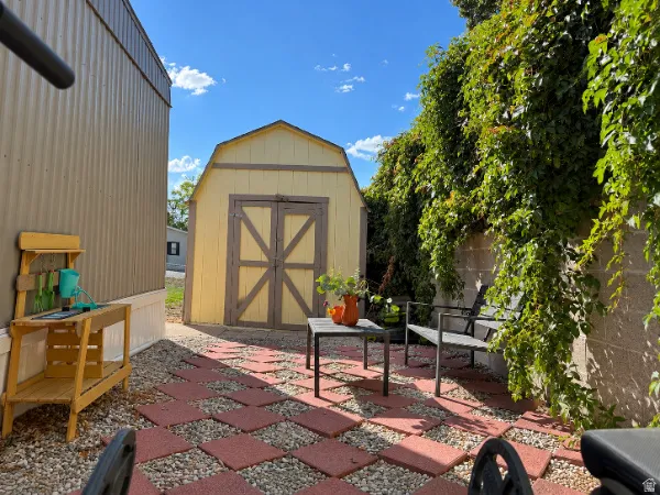 Patio area featuring red paver stones, gravel, and a concrete block wall with climbing foliage
