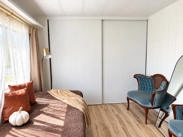 Wood-finish flooring, white paneled wall, and sliding closet doors