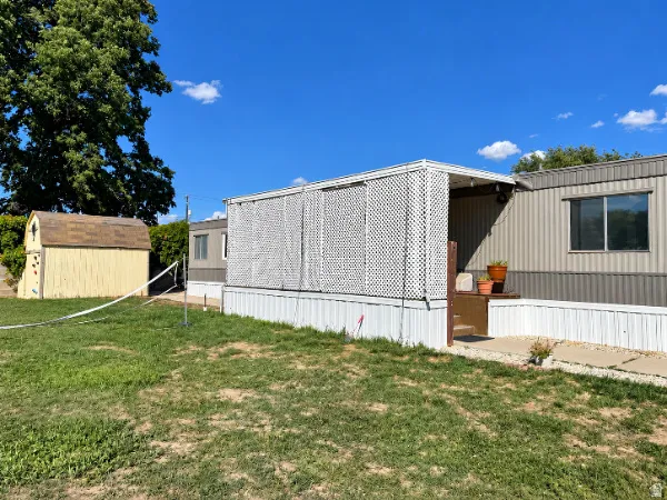 Exterior siding in a two-tone finish, covered entry with lattice screening, and a detached storage shed