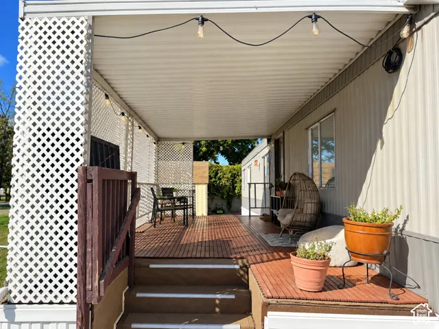 Expansive covered porch featuring a wood-finish deck, white lattice screening, and exterior steps