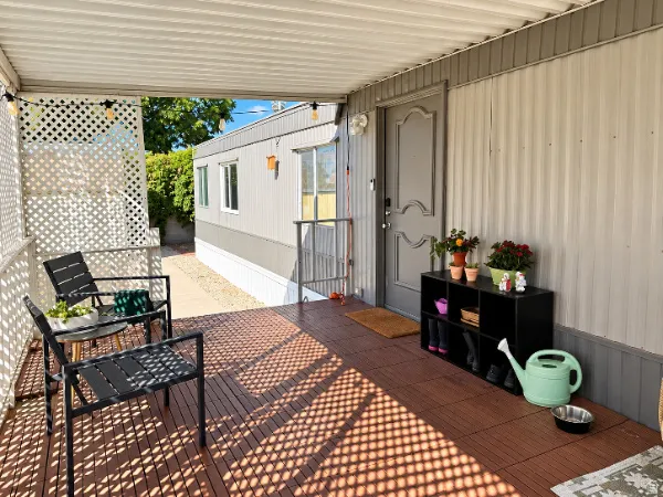 Covered porch featuring brown wood-finish flooring, white lattice privacy screen, and a gray entry door