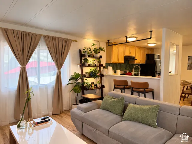 Recessed lighting, wood-finish flooring, light wood cabinetry, and a black appliance package