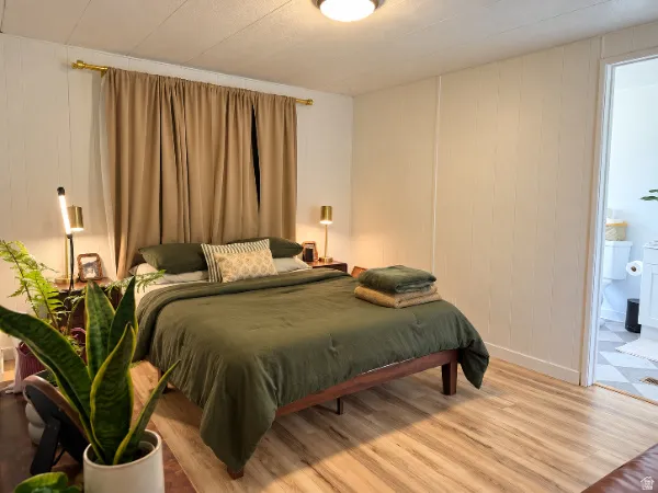 Light wood-finish flooring, white paneled walls, and a warm ceiling light fixture