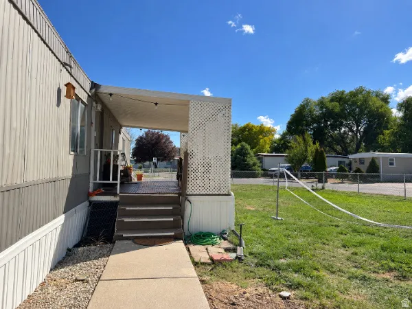 Covered porch entry with lattice detailing, leading to a fenced grassy area