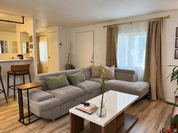 Wood-finish flooring throughout, white walls, and a window with a curtain rod
