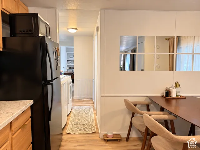 Wood-finish flooring, white paneling on walls, light wood cabinetry, and a flush mount ceiling light