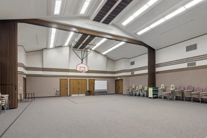 Spacious room with a vaulted ceiling, recessed lighting, carpet flooring, a basketball hoop, and multiple wood-finish doors