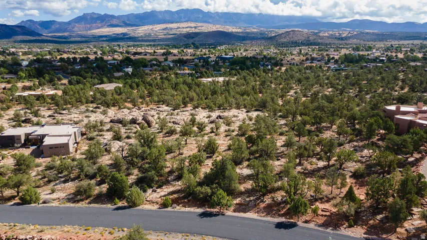 Mountain backdrop, extensive natural landscaping, scattered rock formations, paved road access, multiple trees