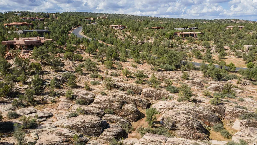 Expansive desert landscape featuring natural rock formations, scattered trees, and a winding paved road