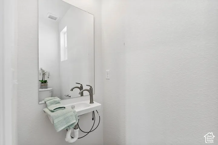 Wall-mounted rectangular sink with a single-handle faucet, set against a large wall mirror