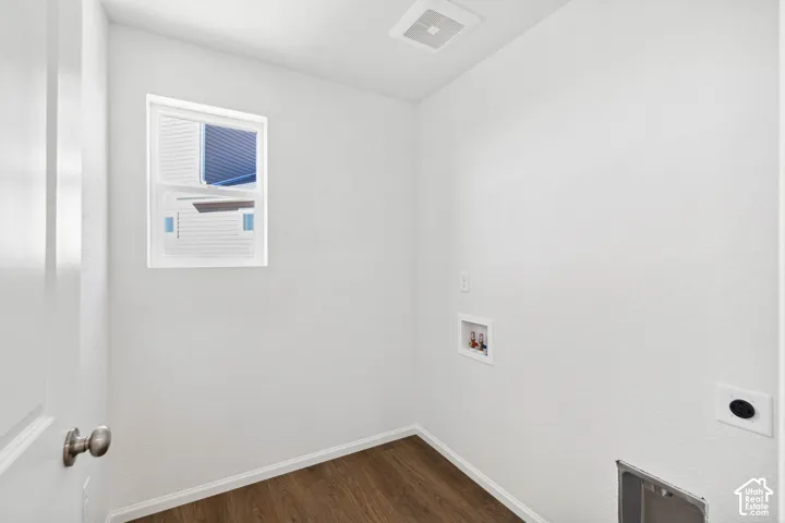 Compact room with wood-finish flooring, a white-framed window, and utility hookups
