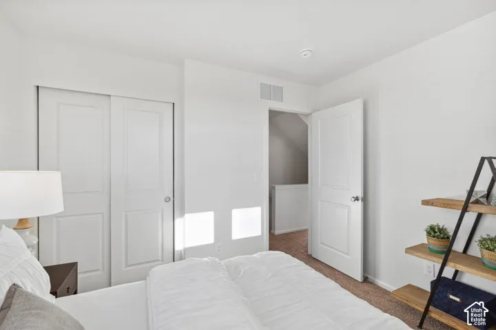 White walls, sliding closet doors, panel interior door, and carpet flooring