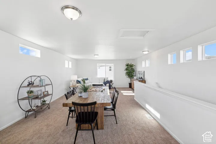 Open-concept living space with light neutral carpeting, multiple windows, and recessed lighting fixtures