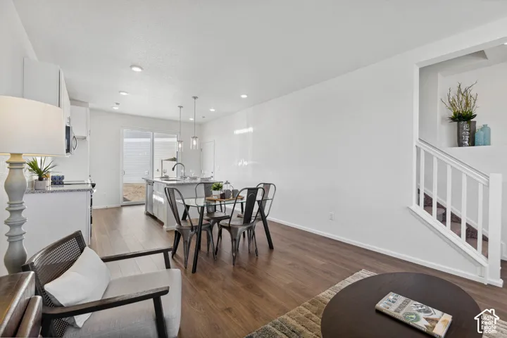 Open-concept living space with wood-finish flooring, recessed lighting, and a white baluster staircase