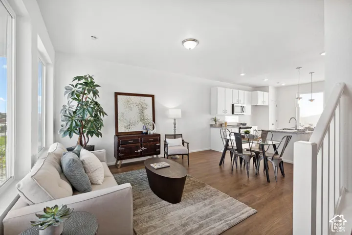 Open-concept living space featuring wood-finish flooring, white walls, and a staircase with white balusters
