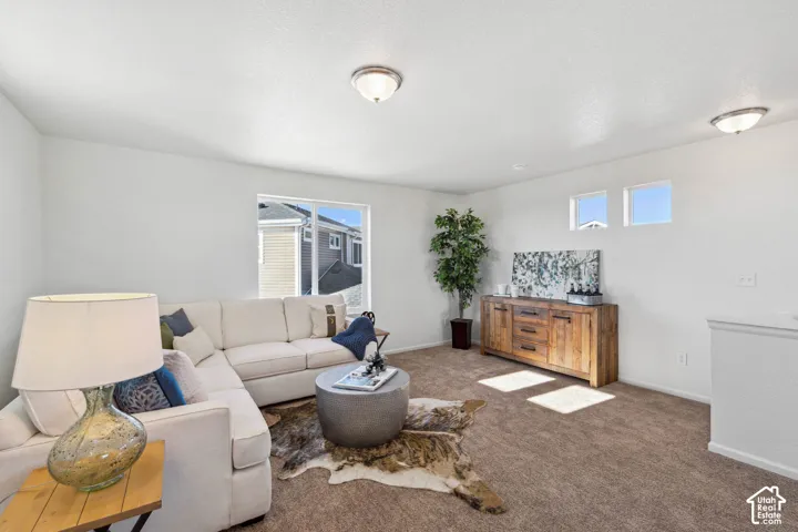 Carpeted living area with white walls, a large window, two upper transom windows, and semi-flush mount lighting