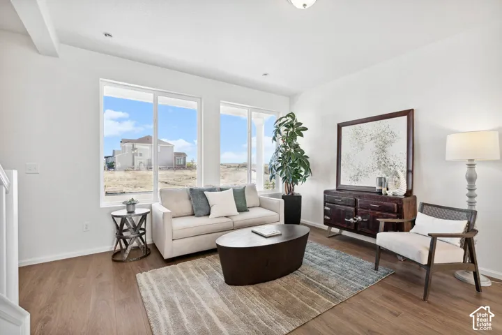 Wood-finish flooring throughout, bright white walls, large windows, recessed ceiling lighting, and a prominent decorative ceiling light fixture