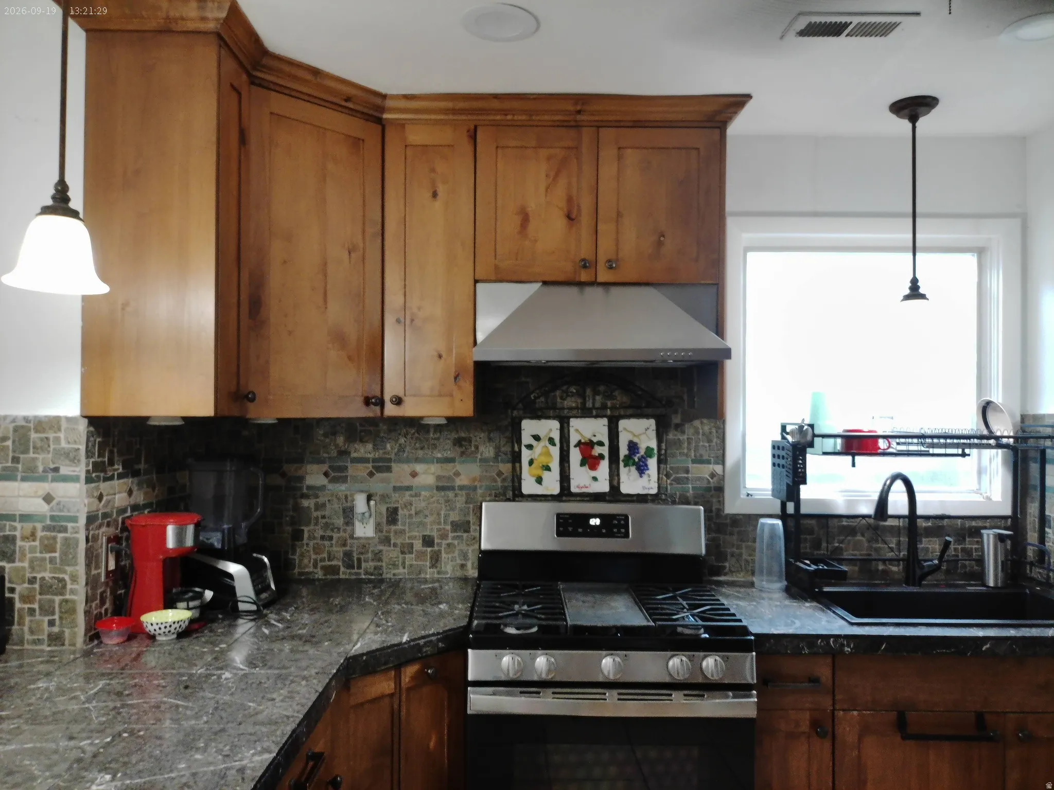 Warm wood cabinetry pairs with stainless steel appliances and a gas range in this updated kitchen