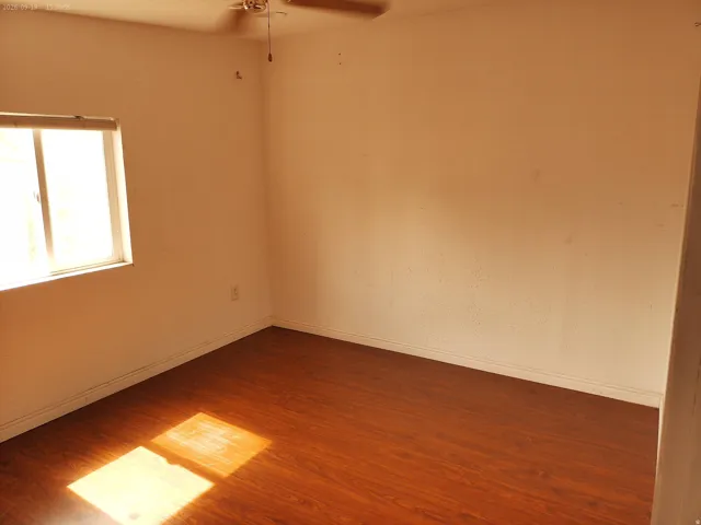Wood-finish flooring with a neutral wall tone and a ceiling-mounted fan