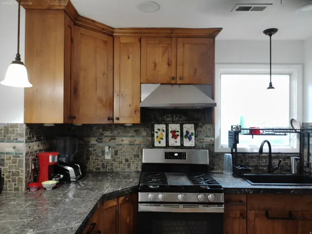 Warm wood cabinetry pairs with stainless steel appliances and a gas range in this updated kitchen