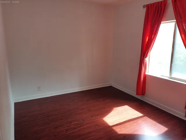 Window with natural light, wood-finish flooring, and white baseboards