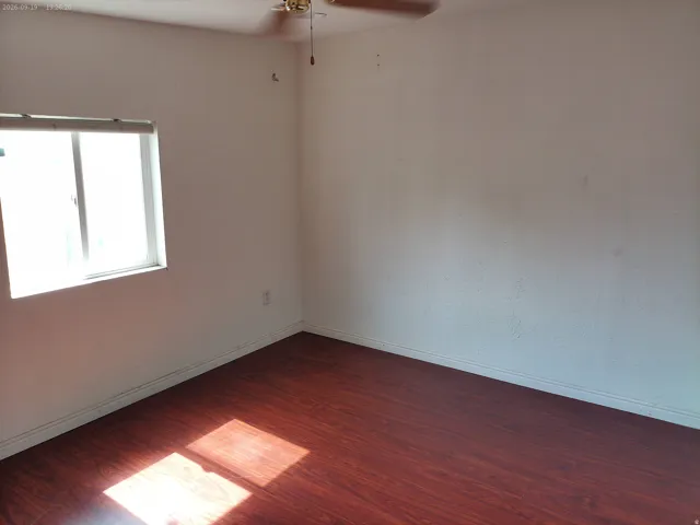 Wood-finish flooring, white walls, and a ceiling fan
