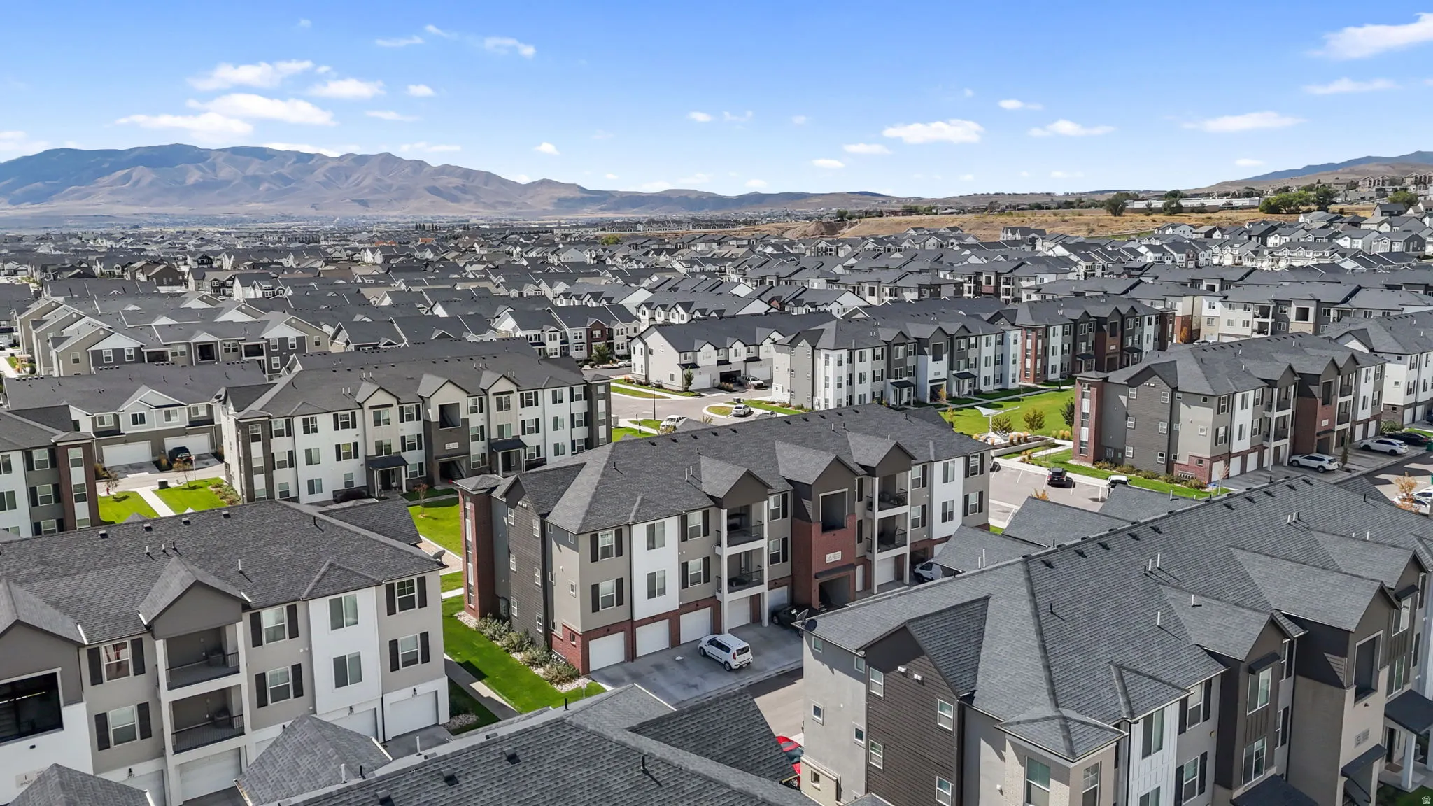 Expansive residential development featuring multi-story buildings with varied facade materials, attached garages, and private balconies
