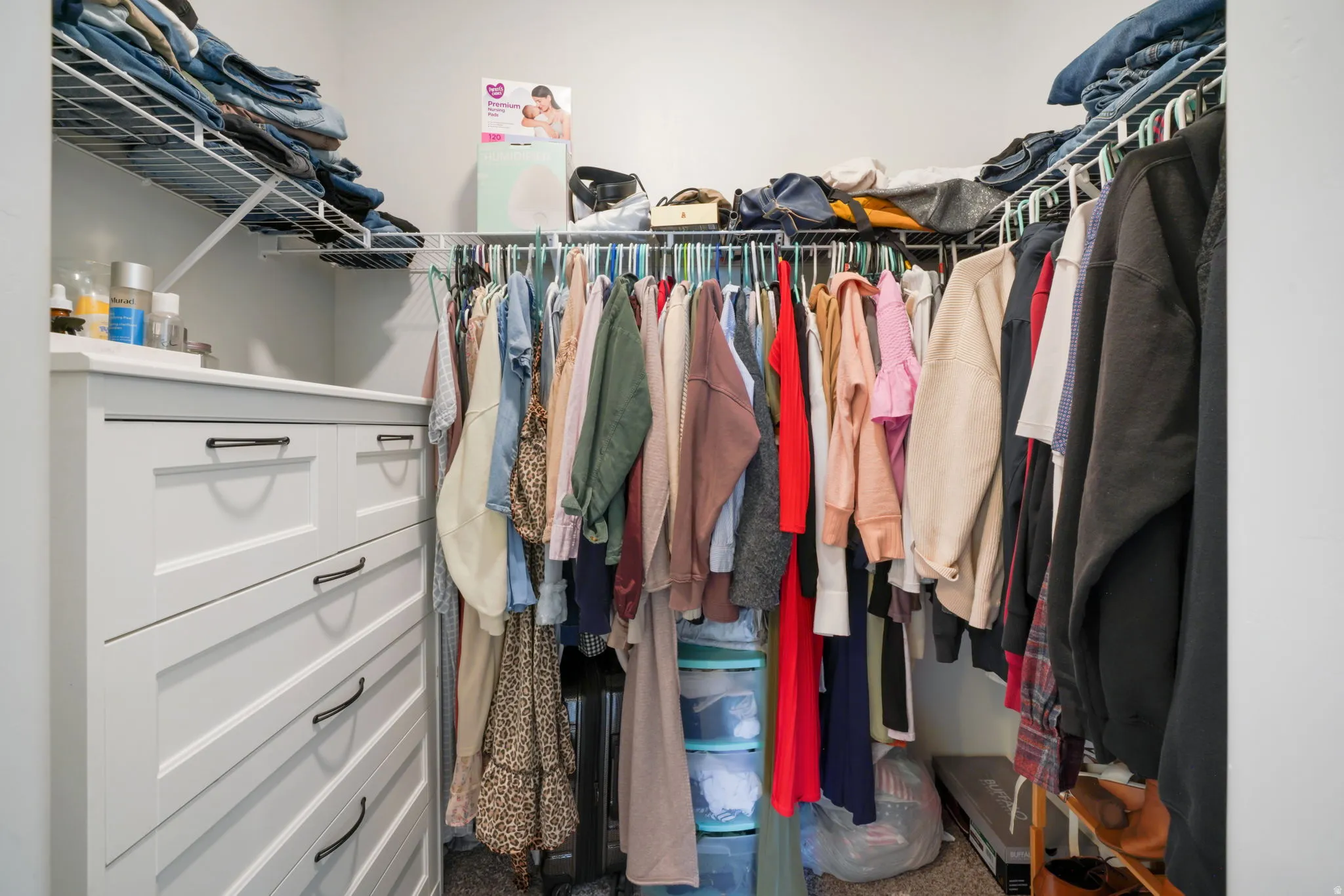 Built-in closet system featuring multiple shelves, hanging rods, and a white dresser with black hardware