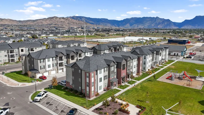 Modern residential development with mountain backdrop, featuring multi-story buildings, dedicated parking, and manicured green spaces